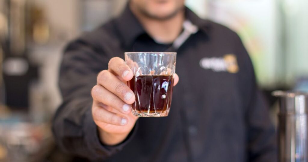 Barista sirviendo café a un cliente en una cafetería